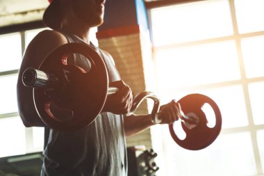 Kaslı bir adamın siluet fotoğrafı spor salonunda halterle egzersiz yapıyor. Kuvvet eğitimi