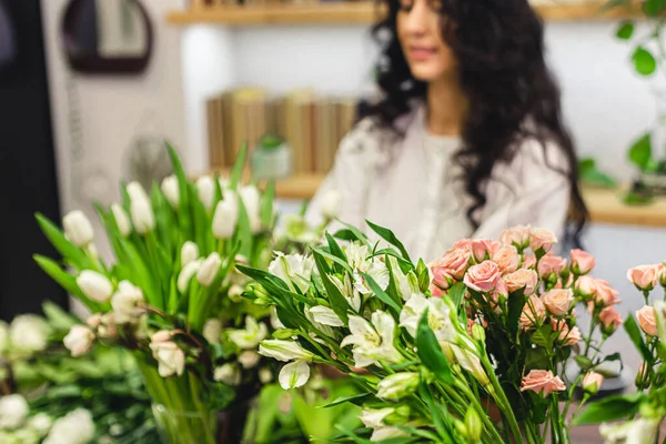 Attractive young woman florist is working in a flower shop.
