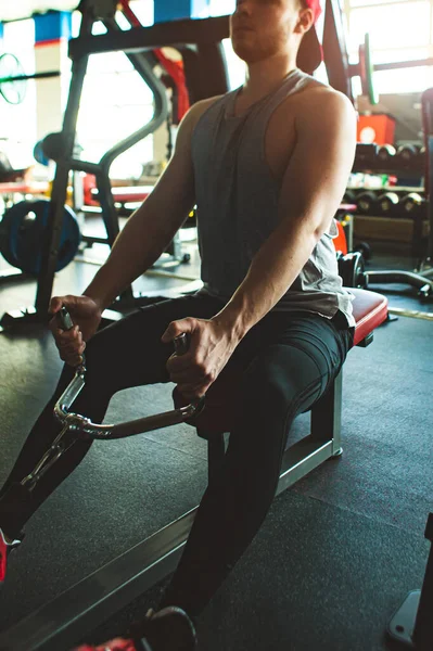 Egy fiatalember edz az edzőteremben. Erő gyakorlatok a szimulátoron — Stock Fotó
