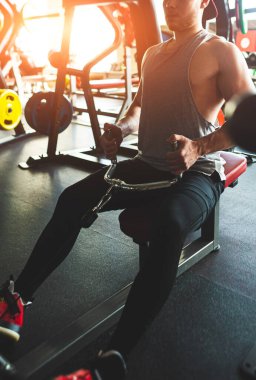 Spor salonunda egzersiz yapan kaslı genç bir sporcu. Simülatördeki kuvvet eğitimi