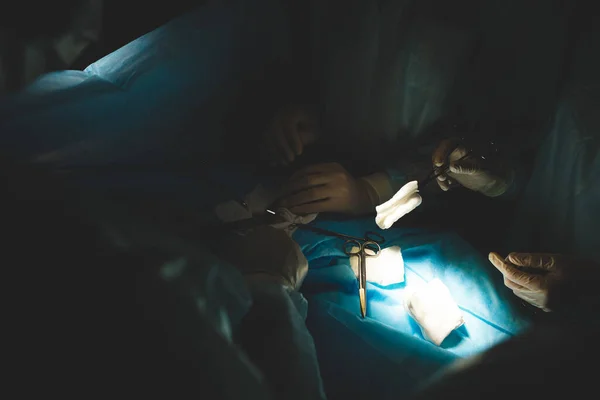 Une équipe internationale de chirurgiens, d'assistants et d'anesthésistes effectue une opération complexe sur un patient sous anesthésie générale. Thème de la photographie atmosphérique sombre en mode discret. — Photo
