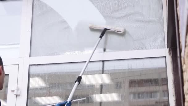 Επαγγελματίας καθαριστής τζαμιών σαπουνίζει και συμπιέζει ένα παράθυρο καθαρό, αρσενικό καθαριστή. — Αρχείο Βίντεο
