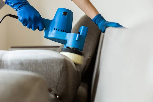 Petugas pembersih kering menghilangkan kotoran dari furnitur di sofa yang datar, tertutup, dan bersih dengan peralatan profesional. membersihkan layanan. — Stok Foto
