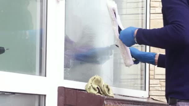 Ein professioneller Fensterputzer seift und drückt ein Fenster sauber, männliche Reinigungskraft. — Stockvideo