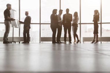 İnsanların siluetleri pencereye dayanıyor. Ofiste birlikte çalışan ve iletişim kuran genç iş adamlarından oluşan bir ekip. Şirket buharı ve bir toplantıda yönetici..