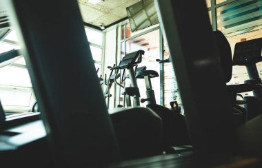 Pencerenin karşısındaki spor salonunda simülatörler çalışıyor. Boş fitness odaları