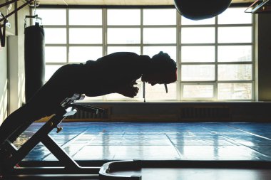 Sporcu pencerenin karşısındaki spor salonunda antrenman yapıyor. Karın egzersizi.