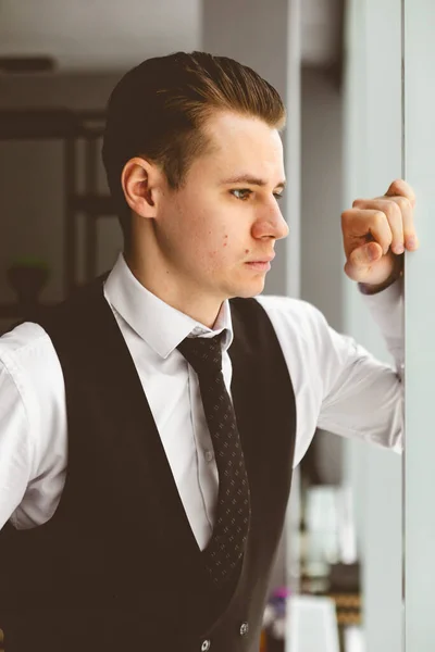 Retrato de un joven empresario con un traje en la oficina. Primer plano de pie junto a la ventana — Foto de Stock