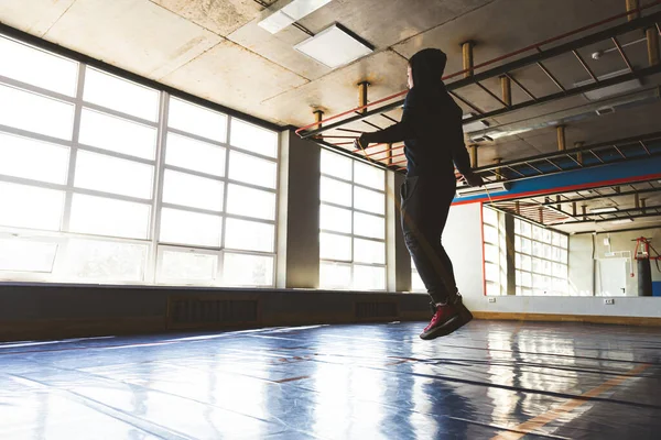 Atleta hombre saltar la cuerda en la sala de entrenamiento en frente de grandes ventanas panorámicas — Foto de Stock