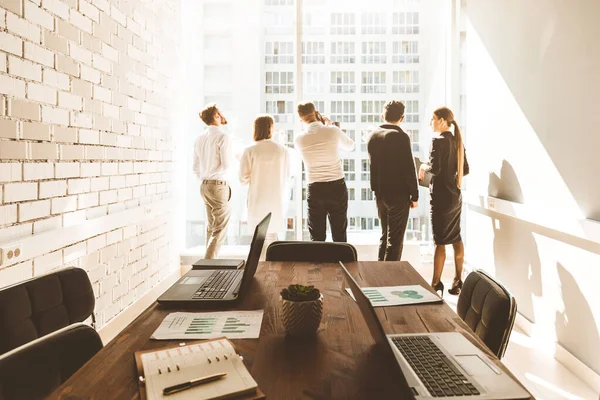 work area on the table in the foreground. A team of young businessmen working and communicating together in an office. Corporate businessteam and manager in a meeting.