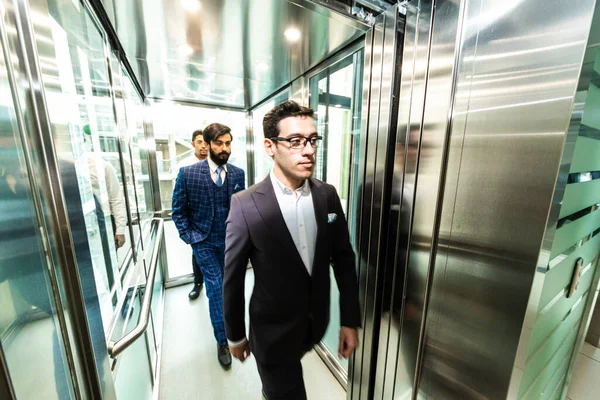 Business team group going on elevator. Business people in a large glass elevator in a modern office. Corporate businessteam and manager in a meeting.