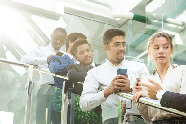 Jóvenes empresarios arego abajo de las escaleras y hablando en el fondo de las oficinas de vidrio. Corporativossteam y gerente en una reunión. — Foto de Stock