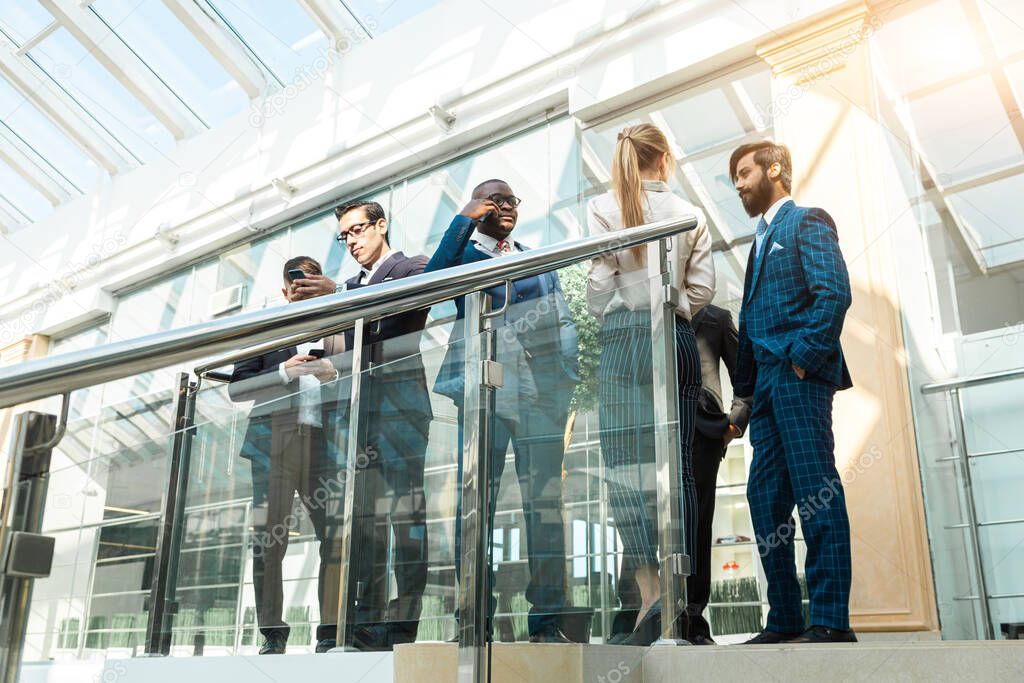 young business people are standing and talking on the background of glass offices. Corporate businessteam and manager in a meeting.