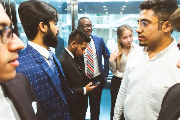 Grupo de negocios en ascensor. Gente de negocios en un gran ascensor de cristal en una oficina moderna. Corporativossteam y gerente en una reunión. — Foto de Stock