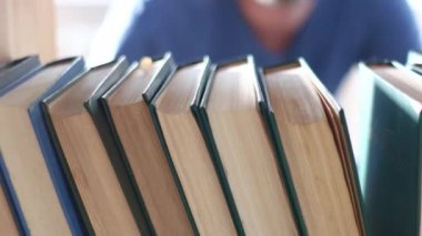 Bir adam kitaplıktan yakın plan bir kitap alır. Bir rafın iç görünümü