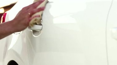 Bir adam arabasındaki nemi ve lekeleri özel bir bezle temizler. Eller yakın plan.
