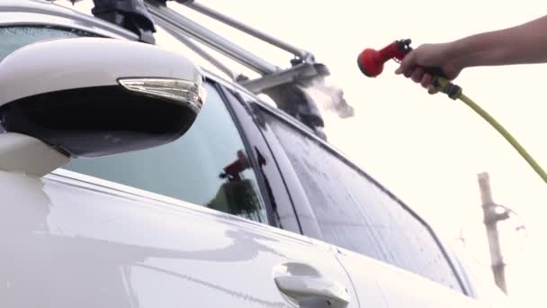 En man tvättar sin sedan från en speciell slang. Manuell bärbar biltvätt. Detaljerad och skonsam bilvård — Stockvideo