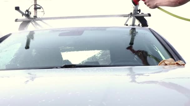 Spălătorie manuală. Un bărbat îşi spală sedanul dintr-un furtun special. Spălătorie portabilă manuală. Îngrijirea detaliată și blândă a mașinii — Videoclip de stoc