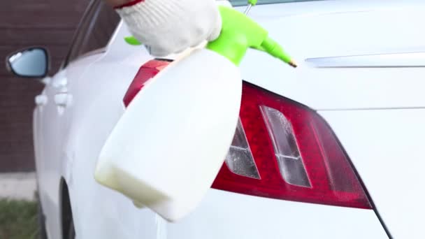 Чоловік миє свій седан спеціальним шампунем. Обприскування миючого засобу на поверхню автомобіля. Догляд за транспортними засобами — стокове відео