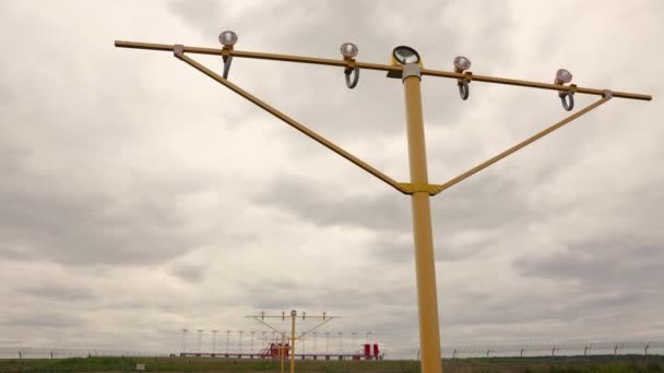 Zeitraffer-Landekurs-Gleitbahnsystem am Flughafen vor dem Hintergrund schwebender Wolken. Beleuchtungsstangen im Vordergrund — Stockvideo