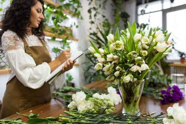 Attractive young woman florist is working in a flower shop.