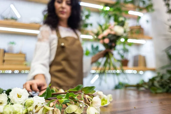 Atractiva florista mujer joven está trabajando en una tienda de flores. — Foto de Stock