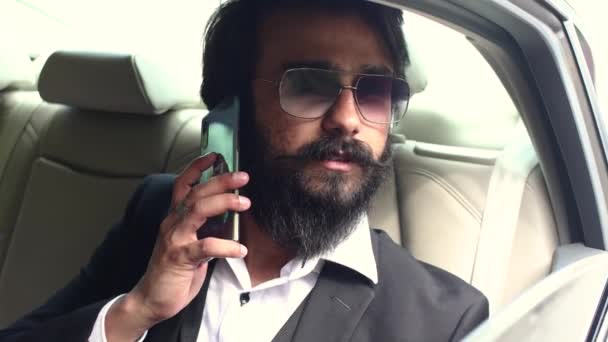 Стильный индийский бизнесмен пользуется телефоном, сидя на заднем сиденье автомобиля . — стоковое видео