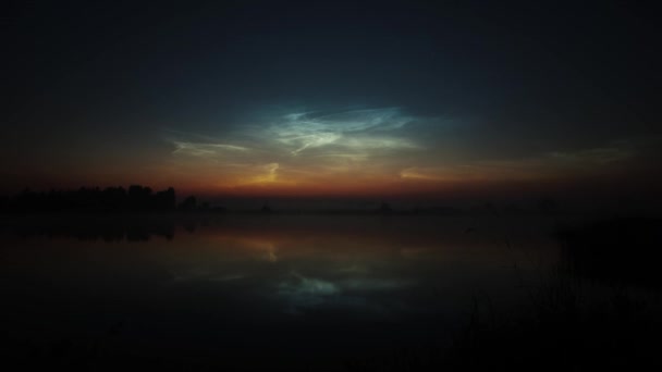 Timelapse zilverkleurige mesosferische wolken boven het meer drijven en worden weerspiegeld in het water — Stockvideo