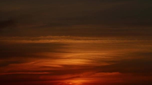 Todas as cores do pôr do sol em um céu nublado em camadas. O sol está tocando o horizonte. Gradiente de cores vermelho-laranja profundo — Vídeo de Stock