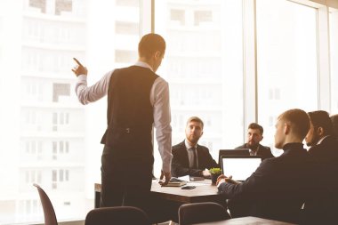 Masada oturan insanların siluetleri. Ofiste birlikte çalışan ve iletişim kuran genç iş adamlarından oluşan bir ekip. Şirket buharı ve bir toplantıda yönetici..