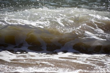 Dalgalar ve köpük sahilde