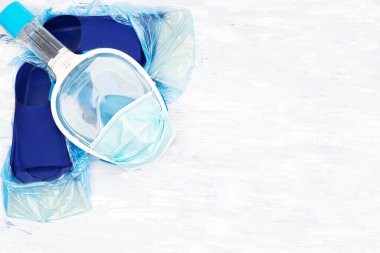 Coronavirüs konseptinin ortasında yaz tatili. Plaj tatillerini ve 2020 yazının seyahat planlarını iptal ettim. Tek kullanımlık yüz maskeli şnorkel maskesi ve koruyucu ayakkabı kılıflı bir çift yüzgeç. Boşluğu kopyala.