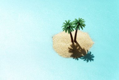 Miniature toy tropical island with palm trees in the ocean. Harsh sunlight effect, copy space. Creative summer vacation concept. clipart