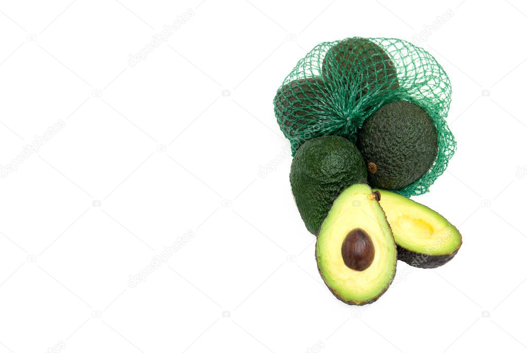 Organic Hass avocados in a green mesh bag isolated on white. One avocado fruit is cut open. Healthy food concept.