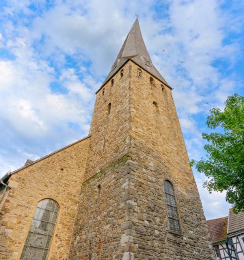 Sivri çatılı ve geniş pencereli taş kilise kulesi Hattingen 'de açık mavi gökyüzüne karşı kurulmuş..