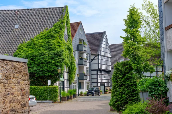 Hattingen, Almanya - 14 Haziran 2025: Hattingen, Almanya 'da geleneksel yarı keresteli evler ve yemyeşil alanlarla dolu Picturesque Caddesi.