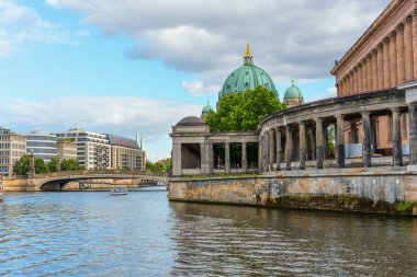 Berlin, Almanya - 17 Ağustos 2025: Tarihi binalar ve parçalı bulutlu gökyüzü altında yeşil bir kubbenin yer aldığı Berlin manzarası.