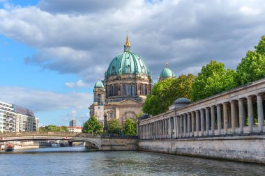 Berlin, Almanya - 17 Ağustos 2025: Berlin, Almanya 'da mavi gökyüzü altında kubbeli, yemyeşil ve nehir manzaralı Berliner Dom Katedrali.