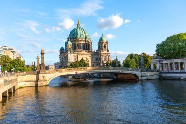 Berlin, Almanya - 17 Ağustos 2025: Berlin Katedrali 'nin muhteşem manzarası, bir köprü tarafından çerçevelenmiş ve parlak bir gökyüzünün altındaki suyu yansıtan çarpıcı bir mimari yapı..