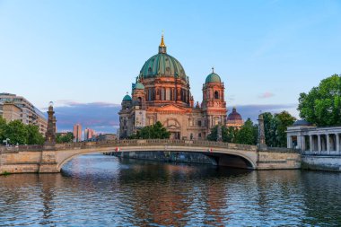Berlin, Almanya - 17 Ağustos 2025: Berlin Katedrali 'nin panoramik manzarası Spree Nehri' ne yansıyan sıcak akşam ışığı altında yıkandı.