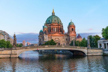 Berlin, Germany - August 17, 2025: Beautiful view of Berlin Cathedral reflected in the Spree River during sunset, with a bridge in the foreground.