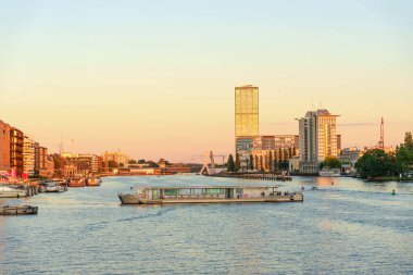 Berlin, Almanya - 18 Ağustos 2025: Berlin 'deki Spree Nehri üzerinde günbatımı, tekneler, modern binalar ve sakin bir atmosfer.