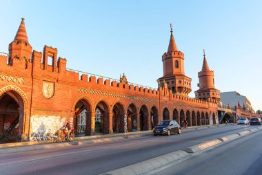 Berlin, Almanya - 18 Ağustos 2025: Oberbaumbruecke köprüsünün kırmızı tuğlalı mimarisi, kuleler ve kemerlerle Berlin 'in özünü gün batımında yakalıyor.