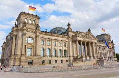 Berlin, Almanya - 20 Ağustos 2025: Berlin 'deki Reichstag Binası' nın dış görünüşü, klasik mimari, bayraklar ve bulutlu bir gökyüzü.
