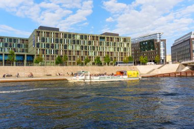 Berlin, Almanya - 20 Ağustos 2025: Güneşli bir günde modern binalarla Spree Nehri 'nde tekne turu.