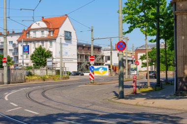 Darmstadt, Almanya - 19 Haziran 2025: Güneşli Darmstadt caddesinde kıvrılan tramvay rayları, trafik ışıkları, binalar ve yeşillikler.