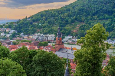 Heidelberg 'in panoramik manzarası. Eski kasaba, seçkin kilise kulesi ve alacakaranlıkta yemyeşil tepeler. Yumuşak ışık, dingin atmosferi yükseltiyor..