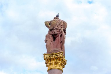 Heidelberg, Almanya - 8 Haziran 2025: Heidelberg, Almanya 'da büyük bir sütunun tepesindeki Herkül heykelinin dikey görüntüsü, bulutlu bir gökyüzüne tünemiş bir güvercin.