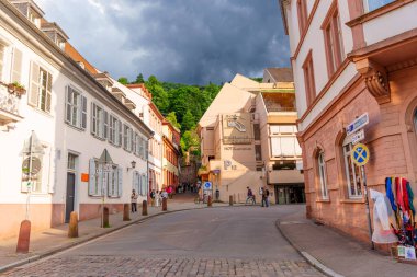 Heidelberg, Almanya - 8 Haziran 2025: Heidelberg 'de geleneksel mimari, kaldırım taşı yolları ve şehrin manzarası üzerinde fırtınalı bir gökyüzü içeren büyüleyici sokak manzarası.