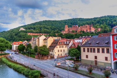 Heidelberg, Almanya - 8 Haziran 2025: Heidelberg, Almanya 'nın panoramik manzarası, tarihi şatoyu, büyüleyici binaları ve bulutlu bir gökyüzünün altındaki Neckar Nehri' ni gözler önüne seriyor.